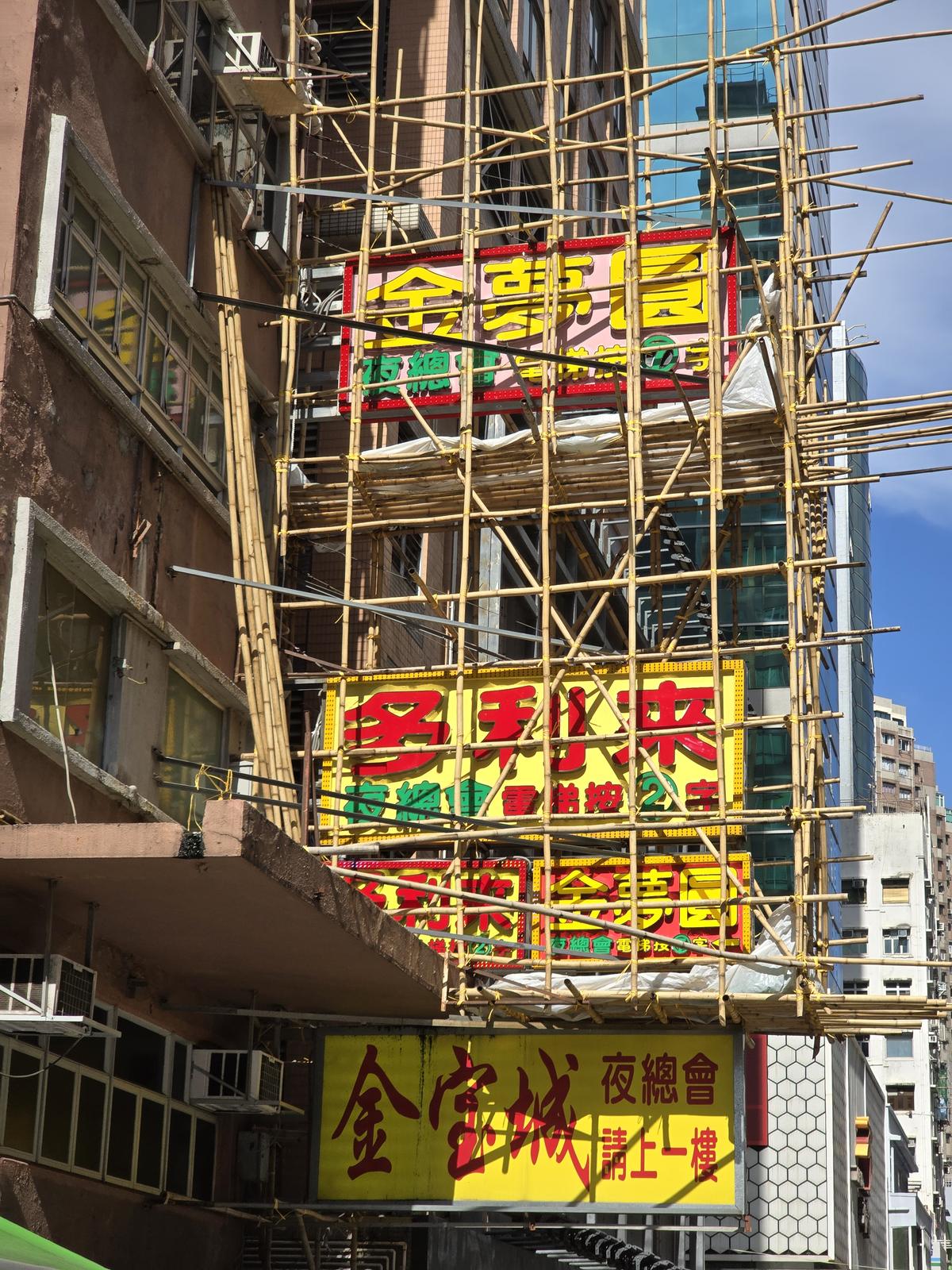 Fachada de Hong Kong con andamios de bambú y letreros de neón